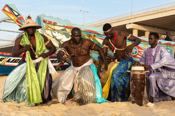 La Lutte-Sportler vor einer bunten Kulisse am Strand von Dakar.