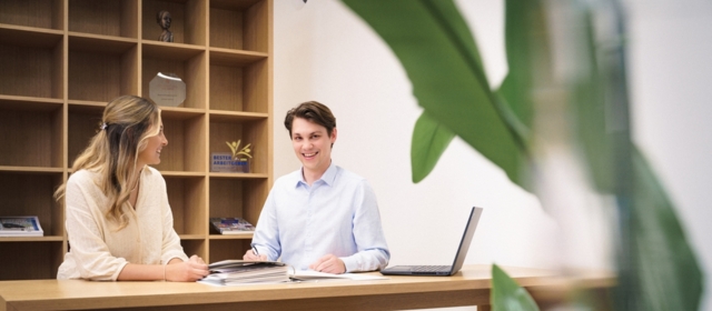 Junge Mitarbeitende arbeiten zu zweit am Hochtisch.